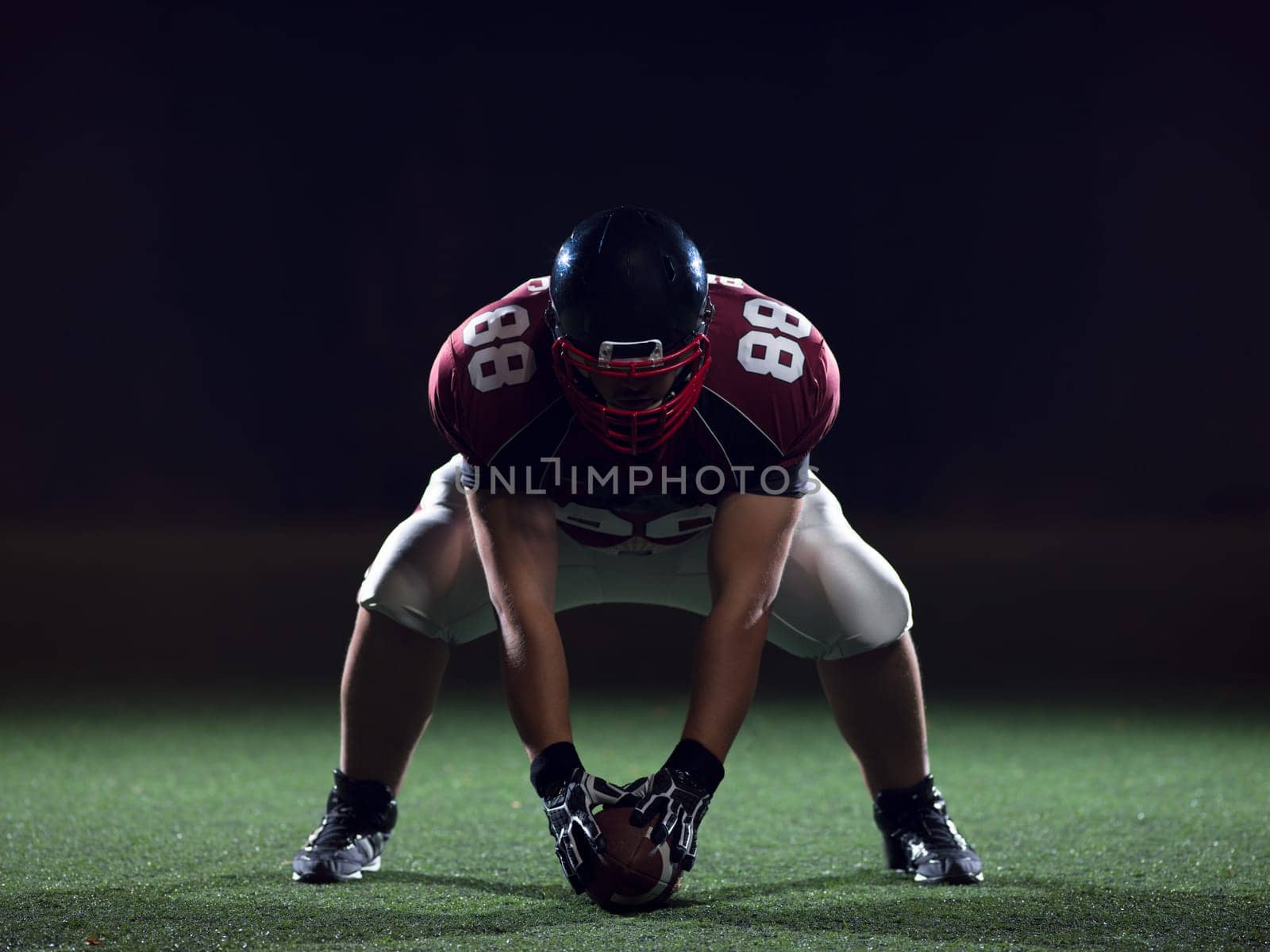 American football player starting football game on american football field at night