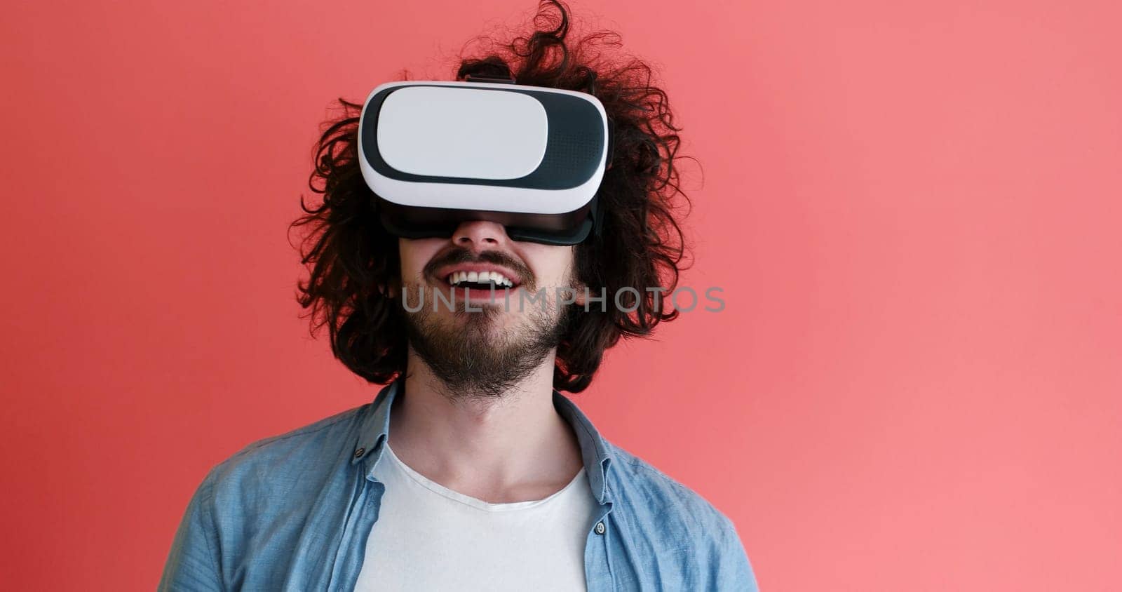 Happy man getting experience using VR headset glasses of virtual reality, isolated on red background