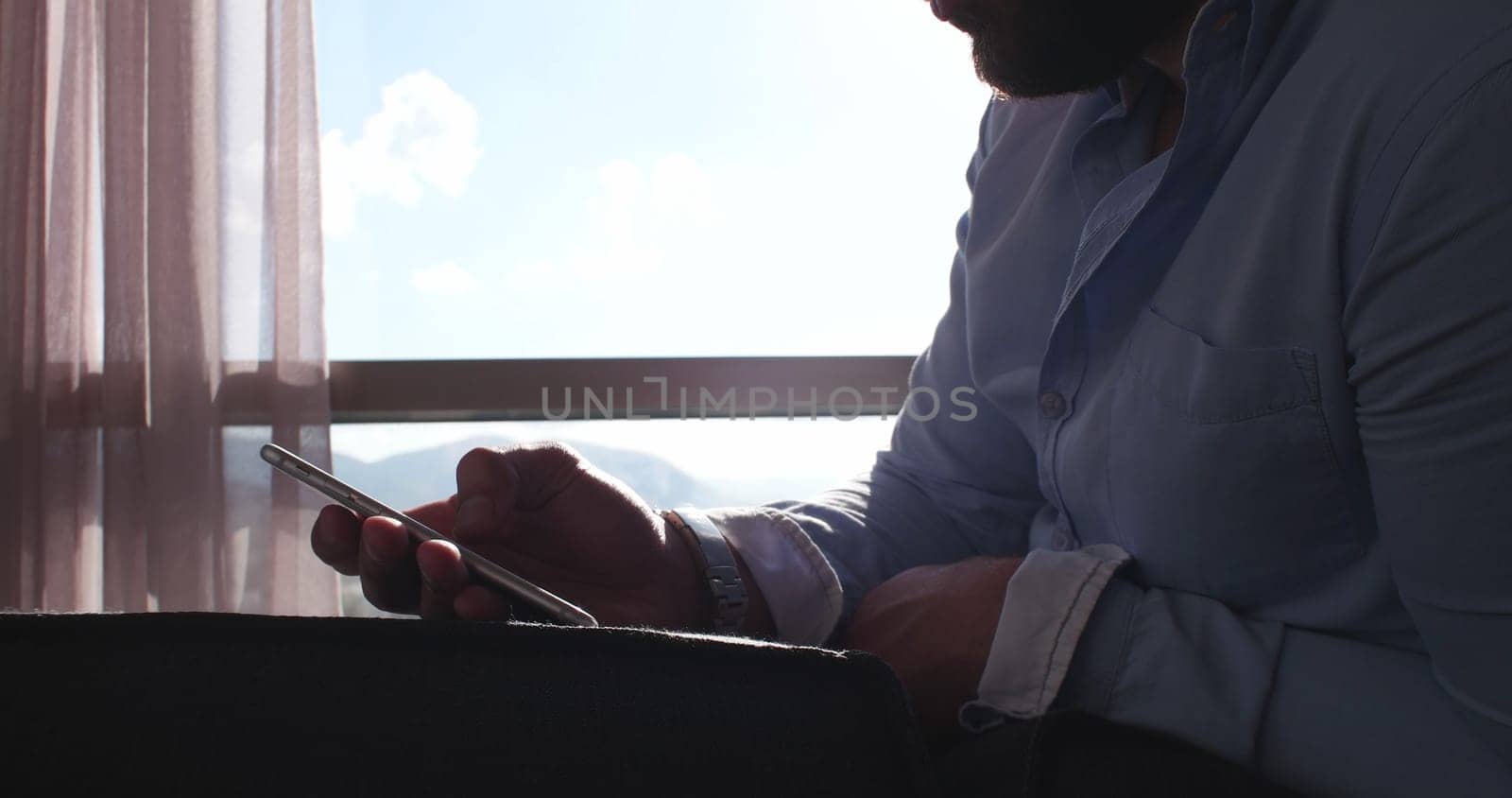 Business Man Talking On Cell Phone At Home with sun flares coming from window