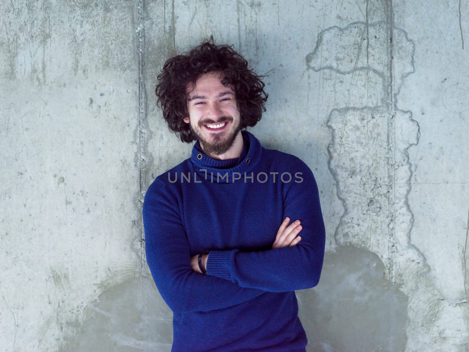 portrait of young successful smiling casual businessman standing in front of a concrete wall at new startup office