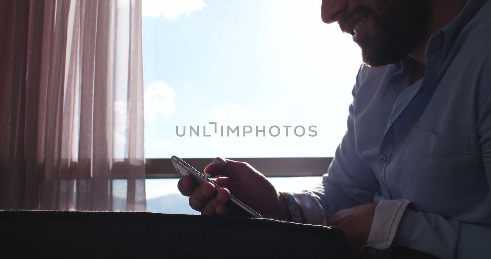Business Man Talking On Cell Phone At Home with sun flares coming from window