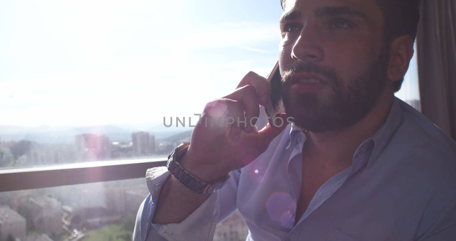 Business Man Talking On Cell Phone At Home with sun flares coming from window