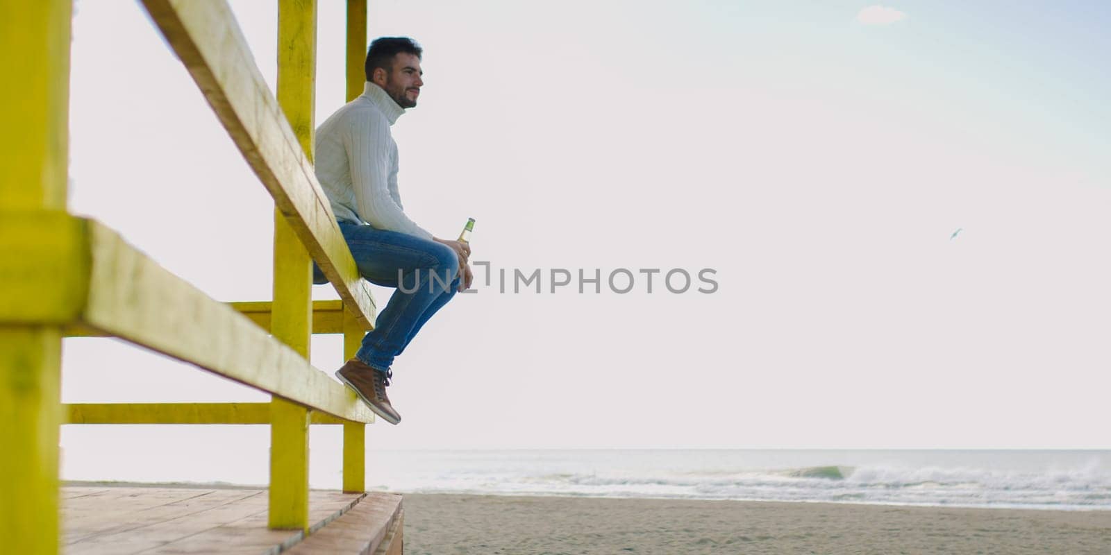 Man Drinking Beer on beach during autumn time