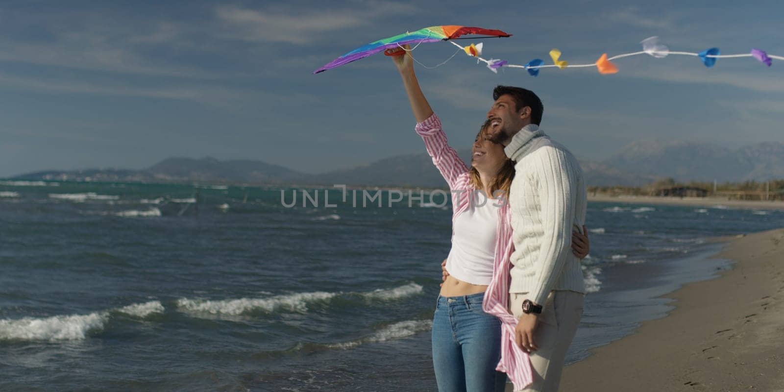 Loving Couple Flying A Kite at Beach and having fun on autumn day