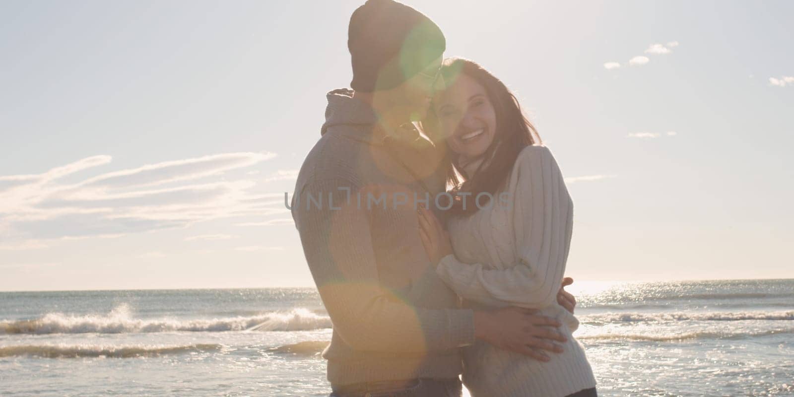 Cool Couple Laughing and hugging In Front Of Beach at beautiful autumn day