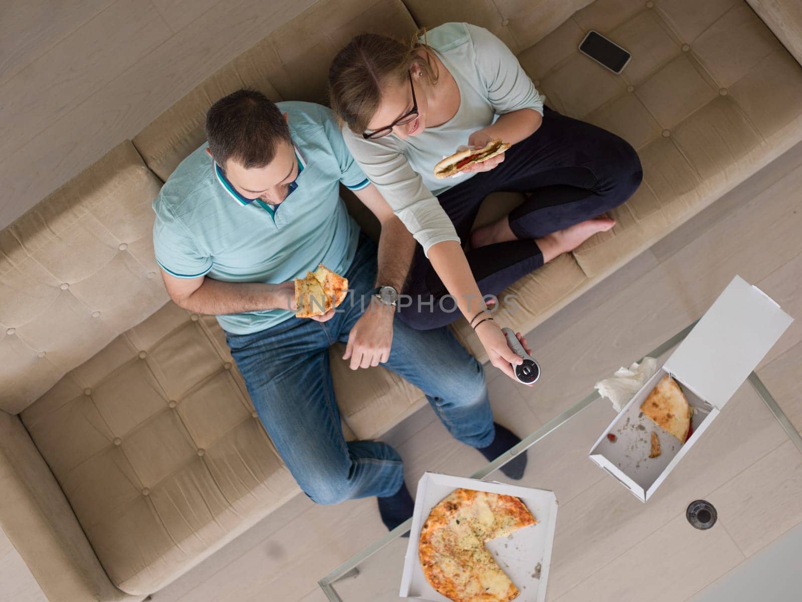young handsome couple cheerfully spending time while eating pizza in their luxury home villa