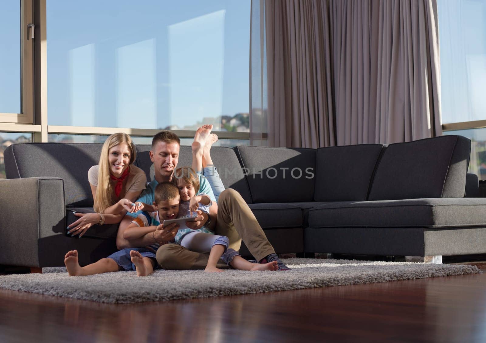 Happy Young Family Playing Together with tablet at home sitting on the sofa