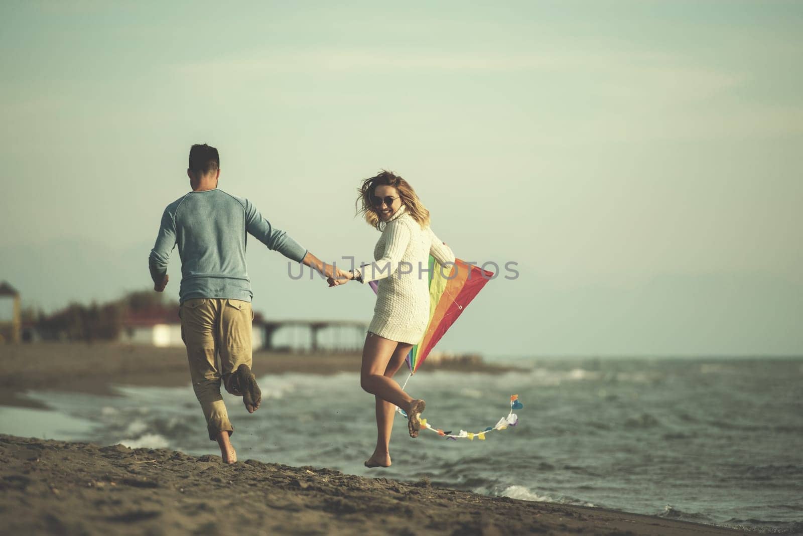 Young Couple having fun and Playing With A Kite On The Beach at autumn day filter