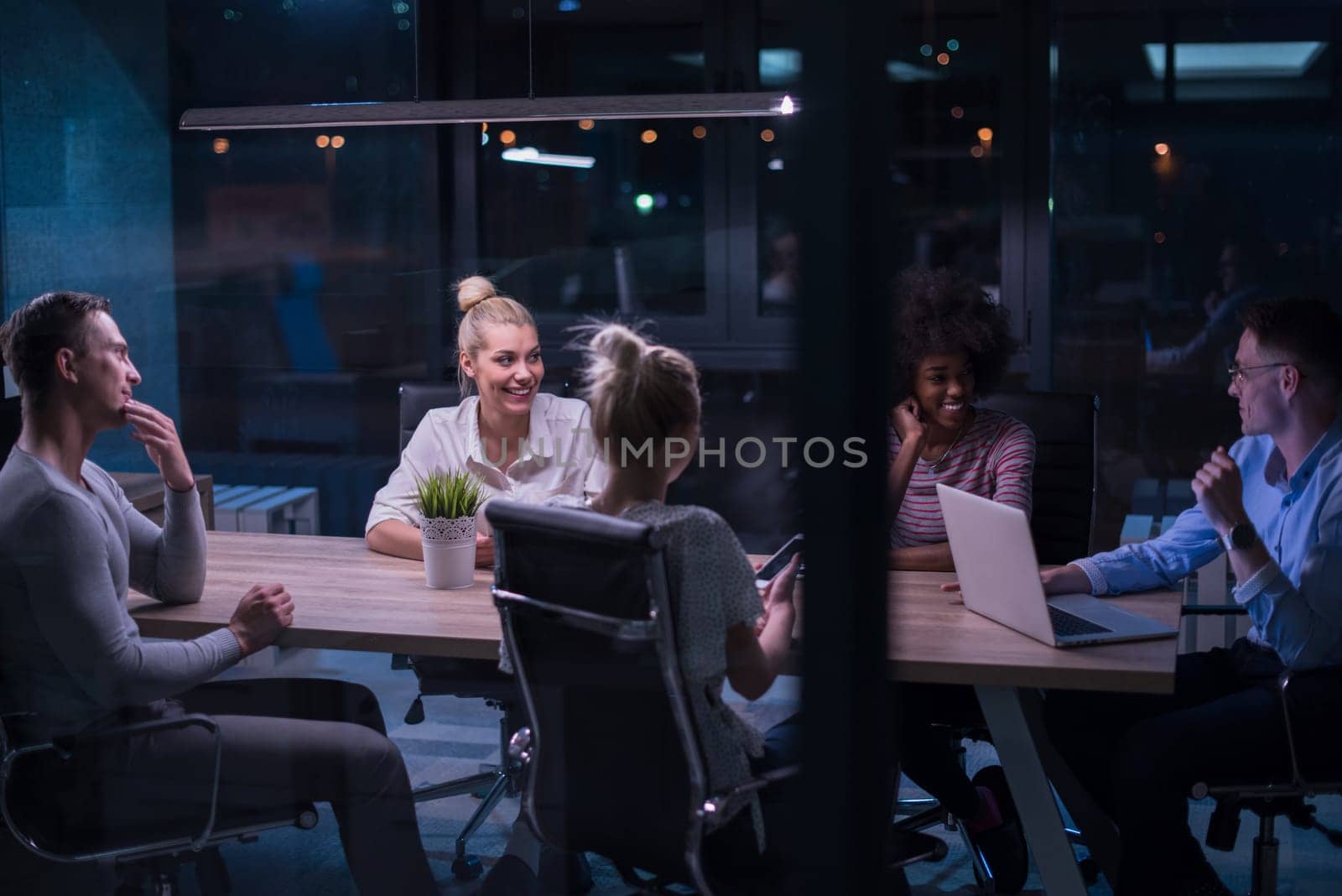 Multiethnic startup business team on meeting in modern night office interior brainstorming, working on laptop