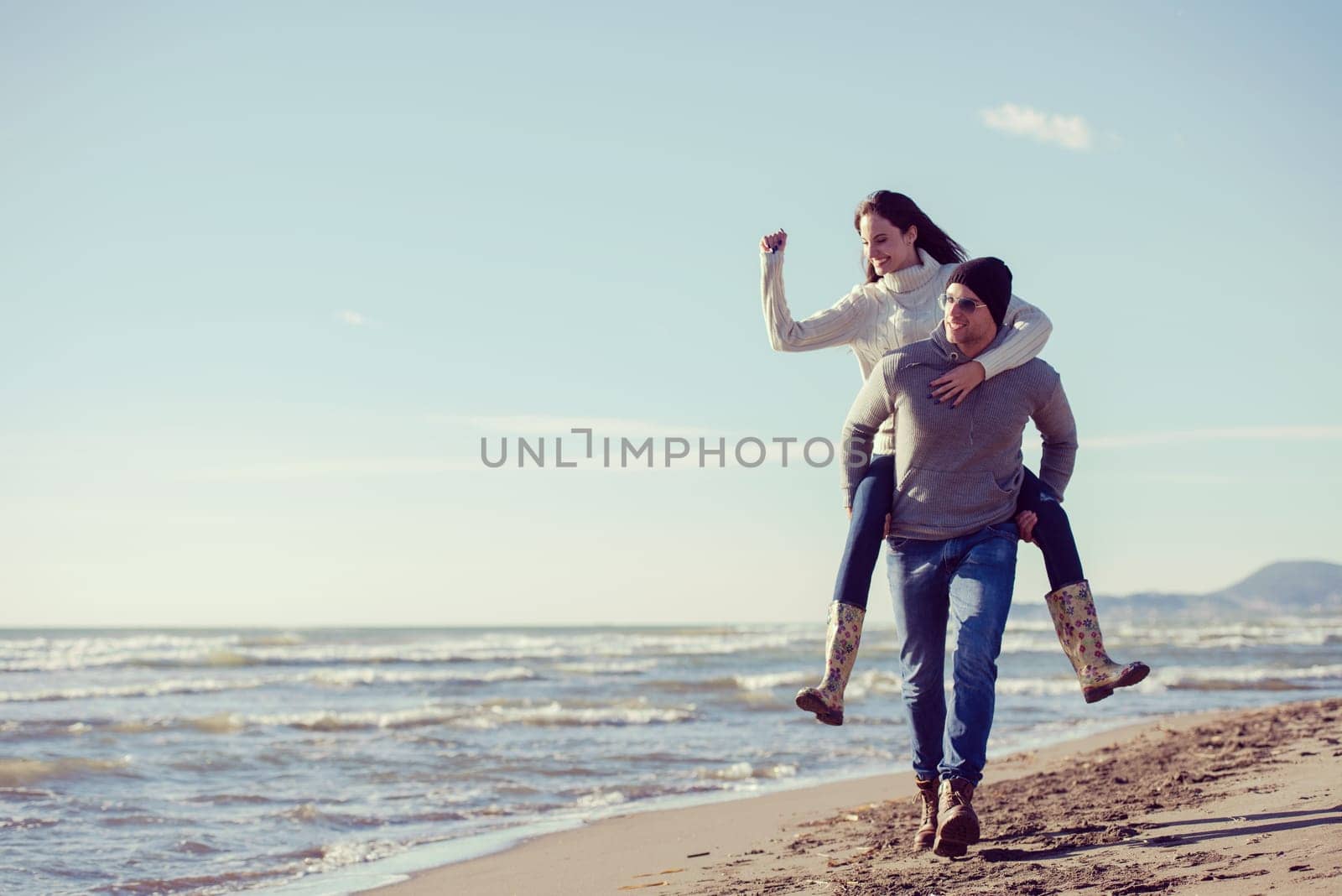 Men Giving Piggy Back Rides his girlfriend At Sunset By The Sea, autumn time