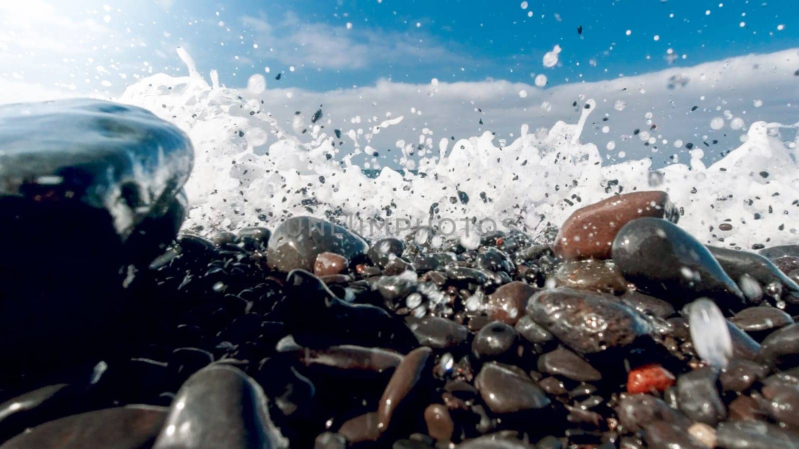 Closeup image of powerful ocean waves breaking and rolling tones and rocks on the sea beach.