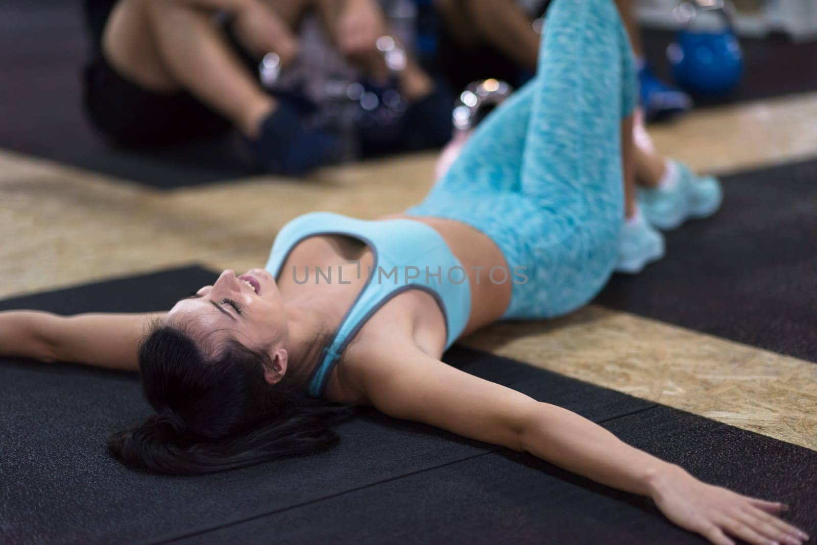 young athlete woman lying on the floor and relaxing before a hard training at cross fitness gym