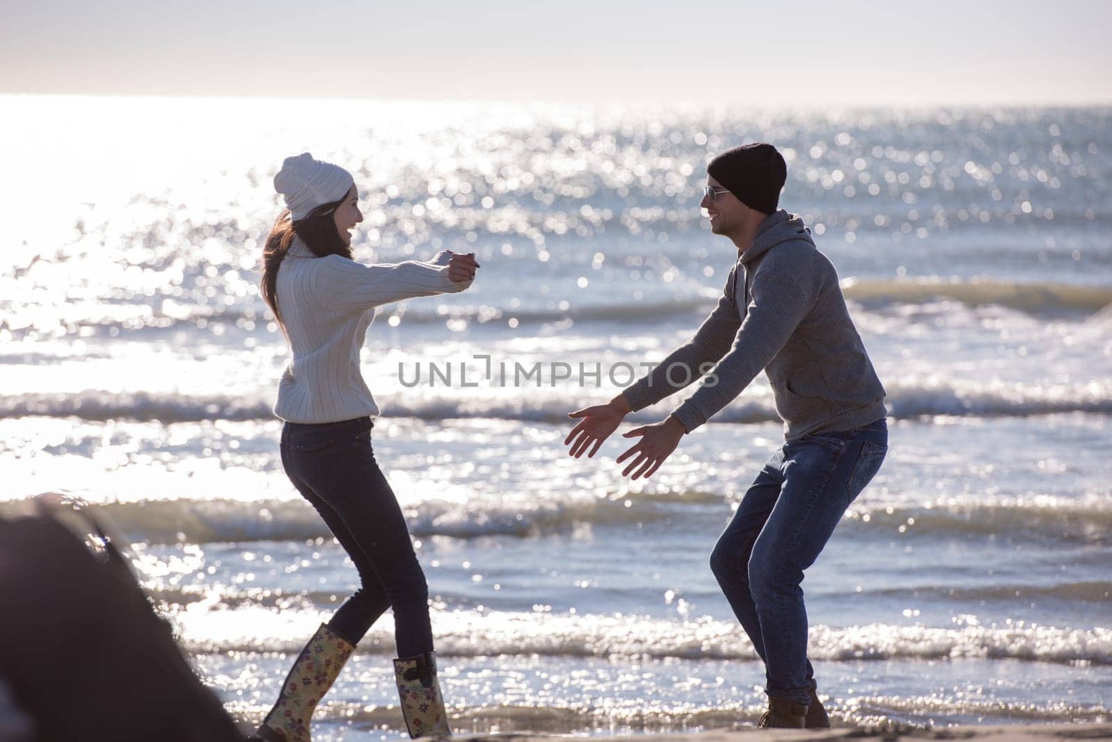 Young couple having fun walking and hugging on beach during autumn sunny day