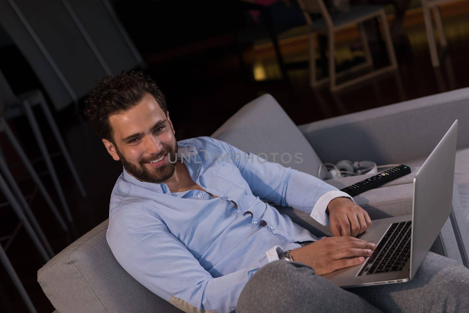 technology, home and lifestyle concept  of man working from home using laptop computer and sitting on sofa