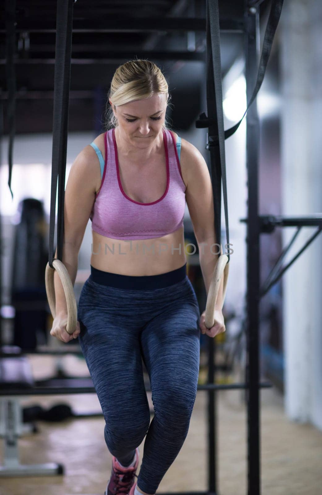young athlete woman working out pull ups with gymnastic rings at the cross fitness gym