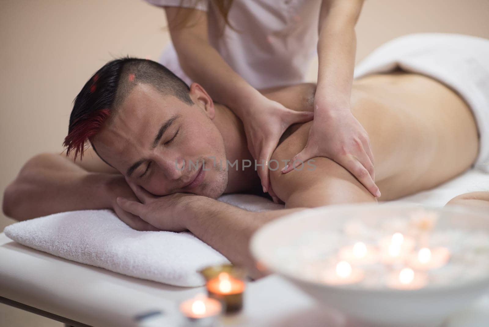 Positive young man having a back massage in a spa center