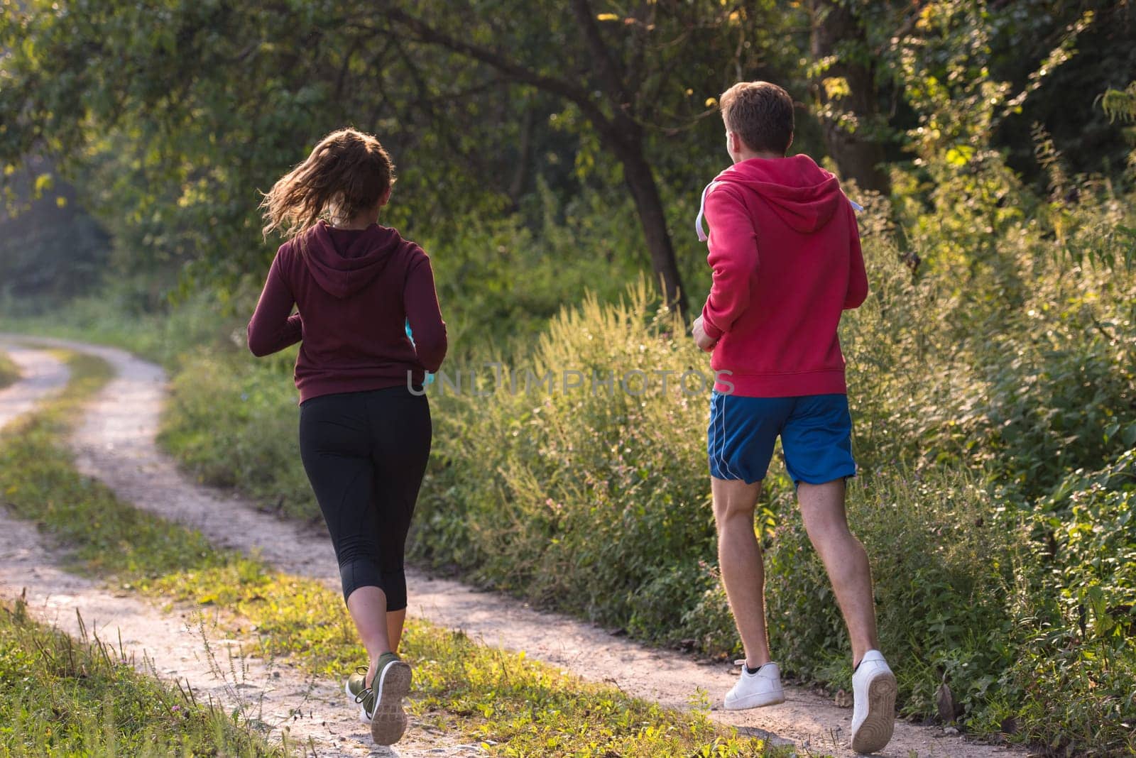 young couple enjoying in a healthy lifestyle while jogging along a country road, exercise and fitness concept