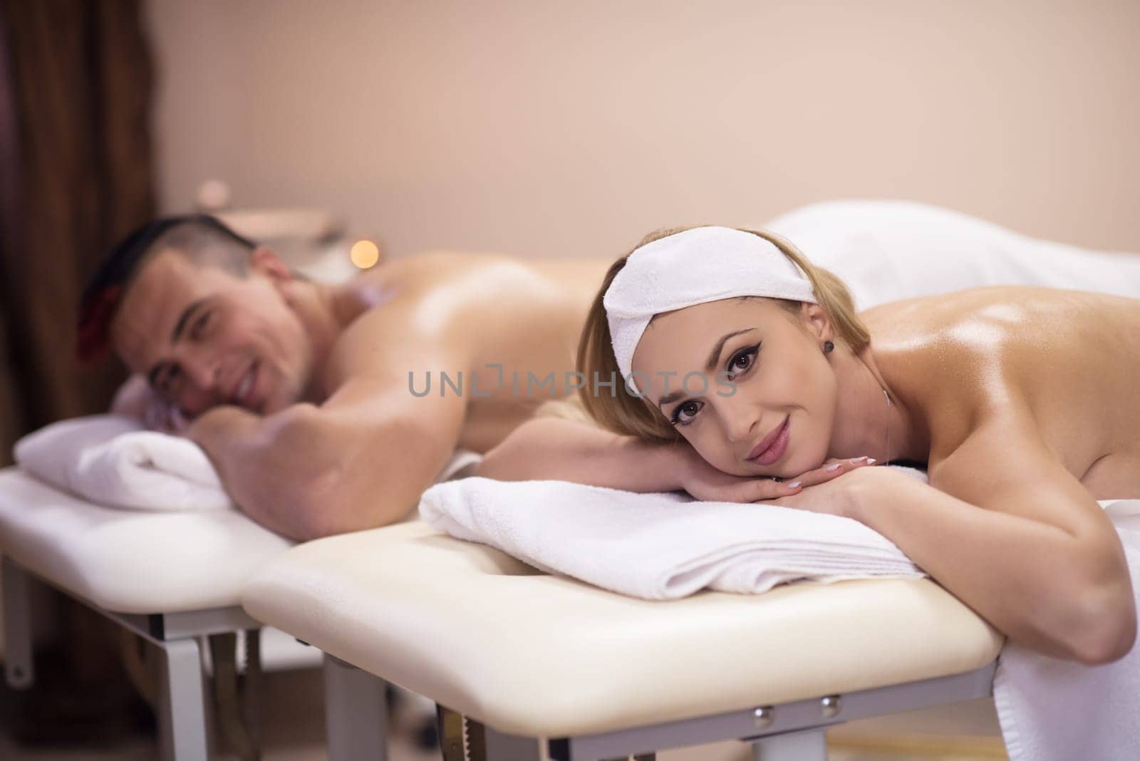 Portrait of relaxed beautiful young couple lying on massage table at spa center
