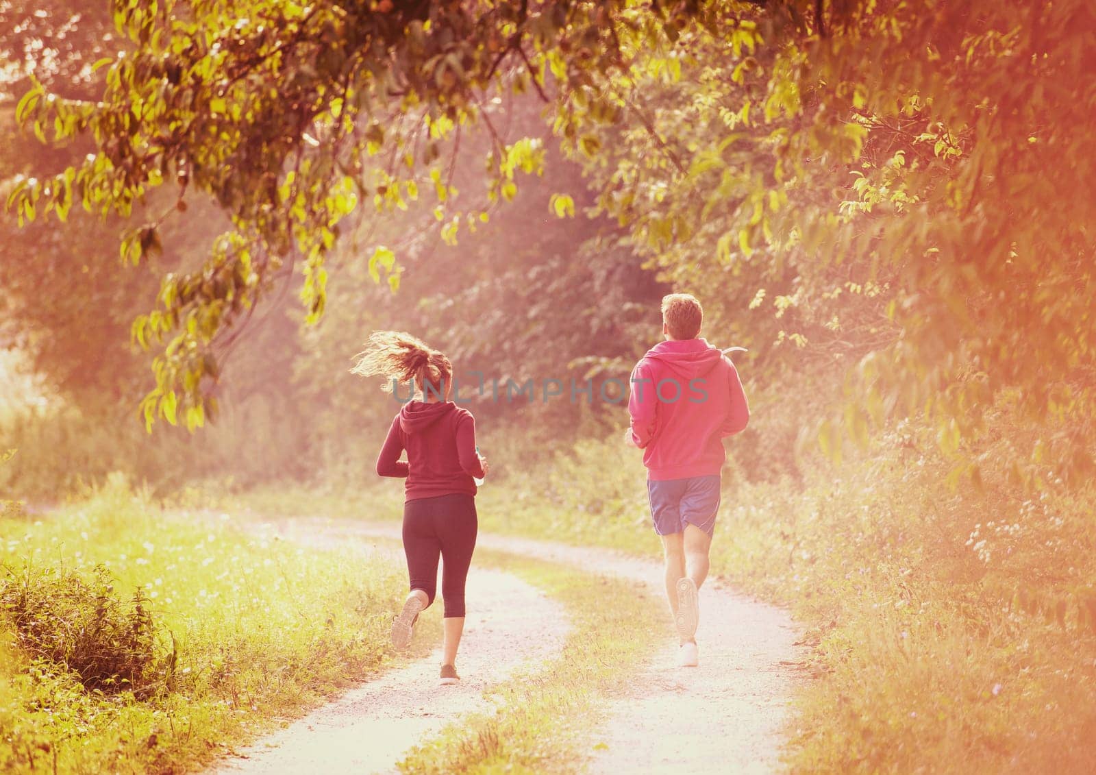 young couple enjoying in a healthy lifestyle while jogging along a country road, exercise and fitness concept