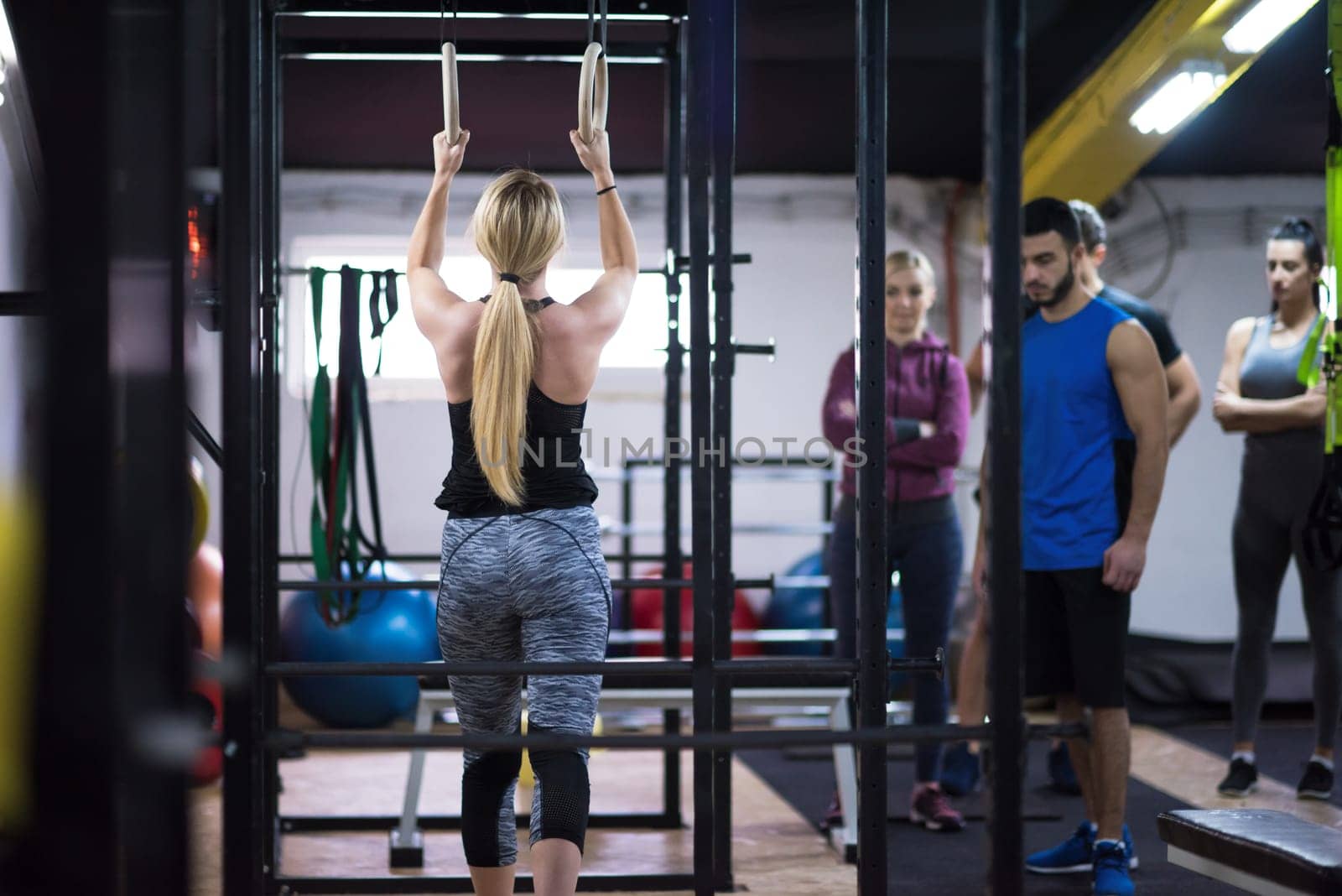 young athletic woman working out with personal trainer on gymnastic rings at the cross fitness gym