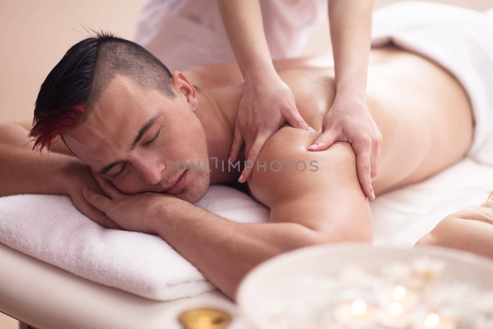 Positive young man having a back massage in a spa center