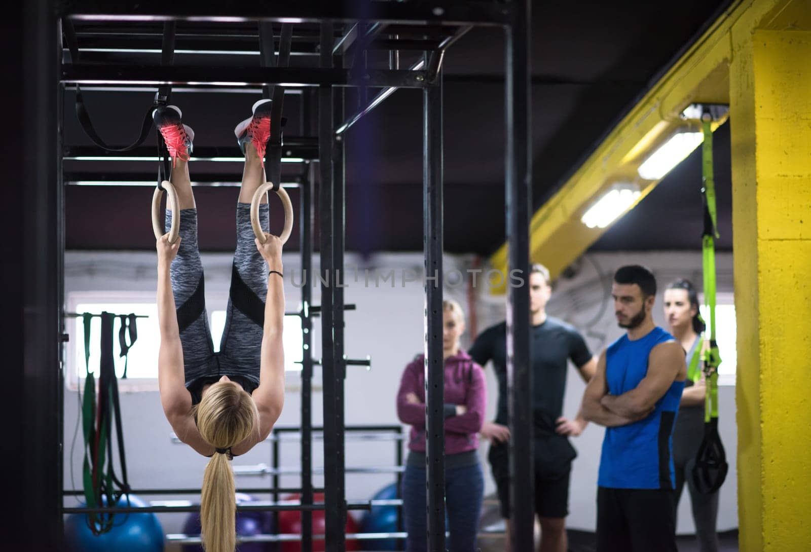 young athletic woman working out with personal trainer on gymnastic rings at the cross fitness gym