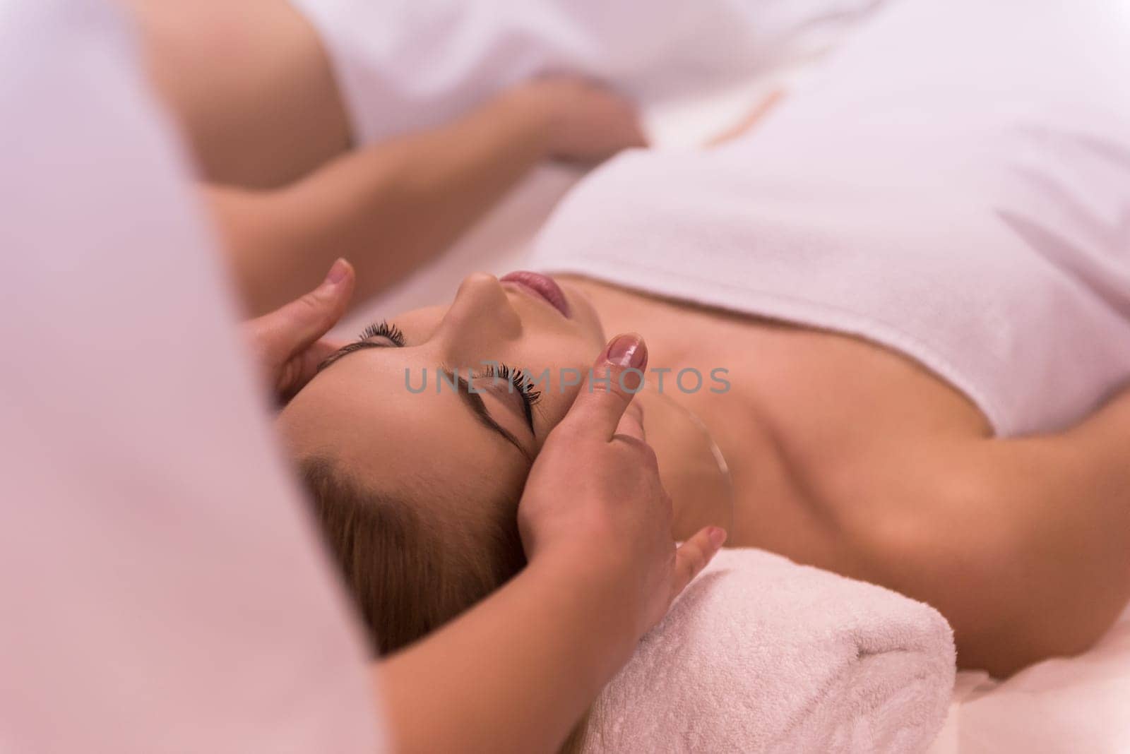 Young beautiful relaxed woman receiving a head massage in a spa centre