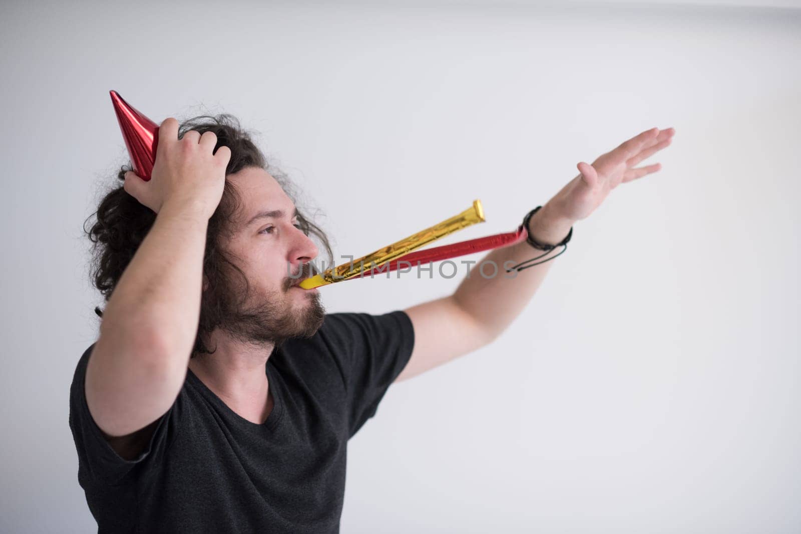 Portrait of a man in party hat blowing in whistle isolated on a white background