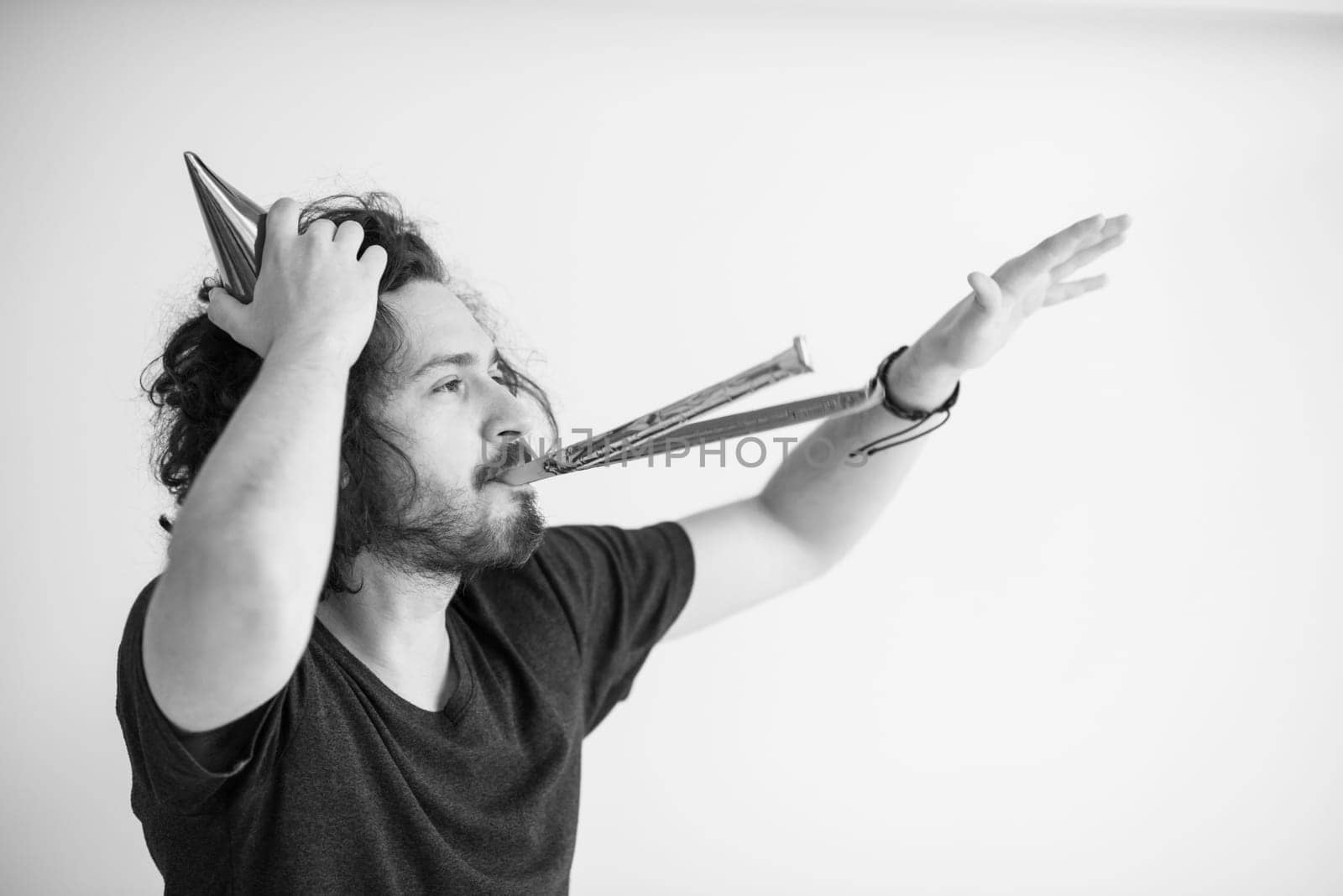 Portrait of a man in party hat blowing in whistle isolated on a white background