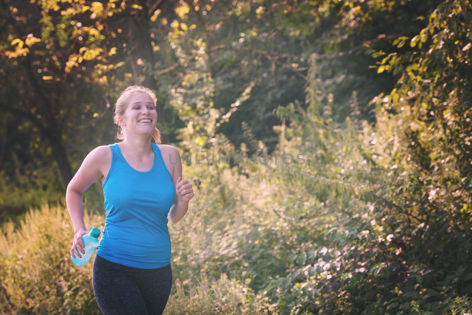 young woman enjoying in a healthy lifestyle while jogging along a country road, exercise and fitness concept