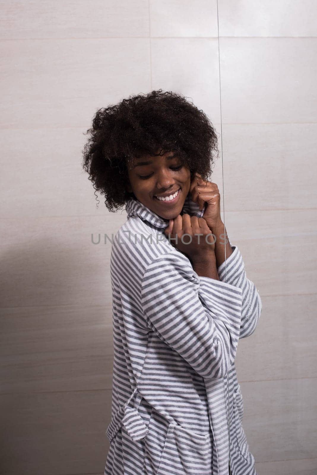 Portrait of young beautiful black woman wearing  bathrobe standing in the bathroom