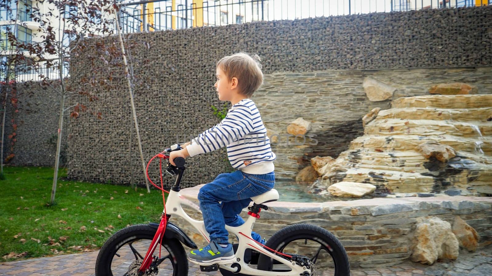 Happy cheerful boy with helmet riding bicycle on street.