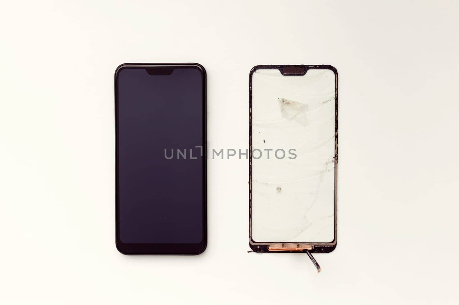 Repair and replacement of a mobile phone touchscreen. Refurbished smartphone and non-working touchscreen on a white background. View from above