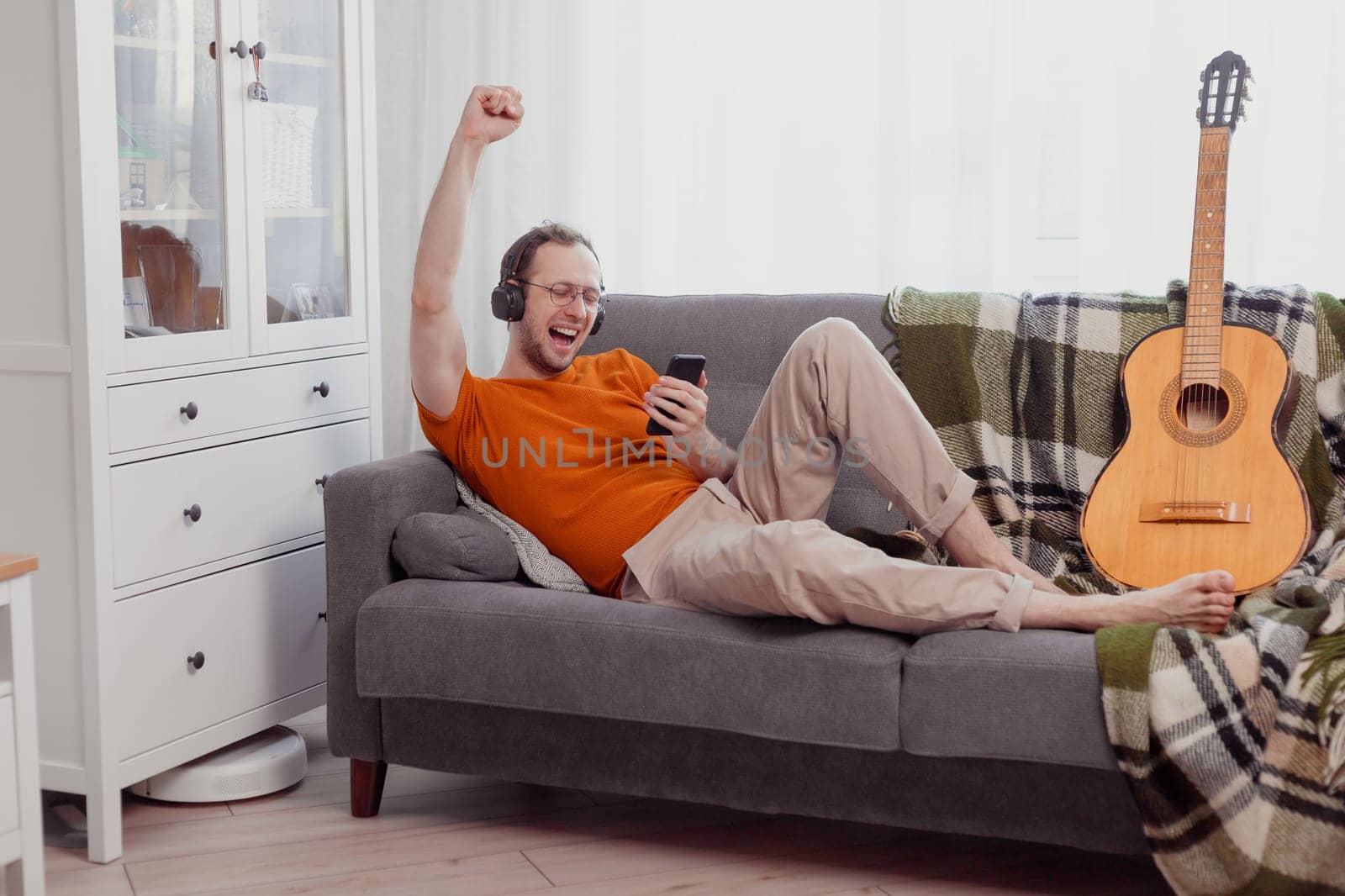 Handsome man playing on the guitar on the couch at home