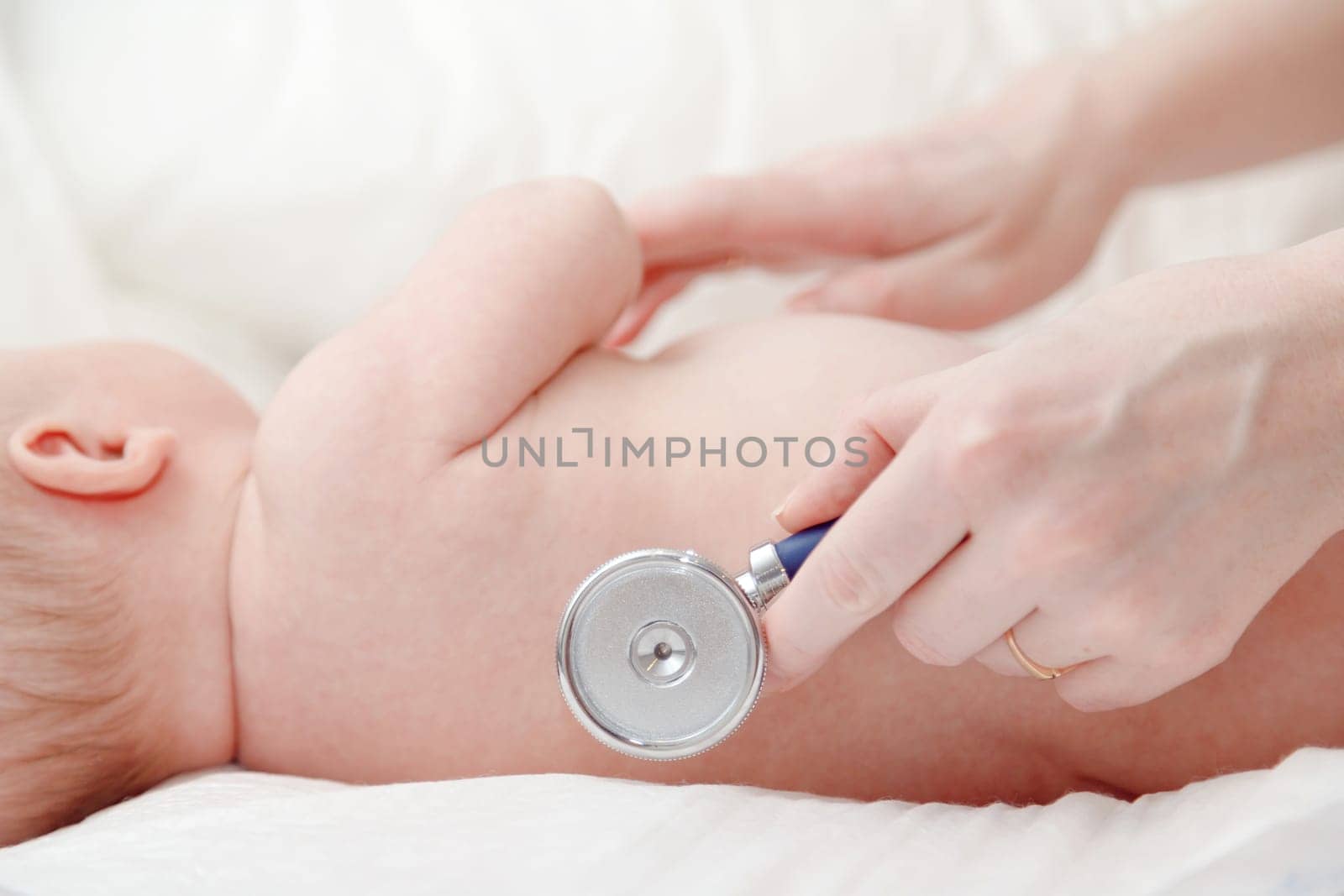 Stethoscope listening to baby newborn's heart beat or lungs. Infant healthcare appointment with a pediatrician