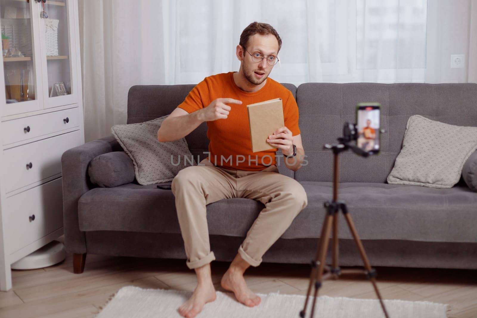 Handsome man blogger at home presents book while video stream. Social media marketing and online sales.