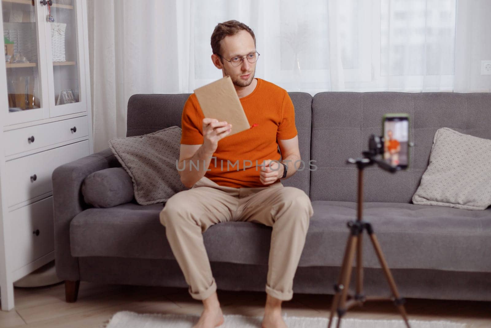 Handsome man blogger at home presents book while video stream. Social media marketing and online sales.