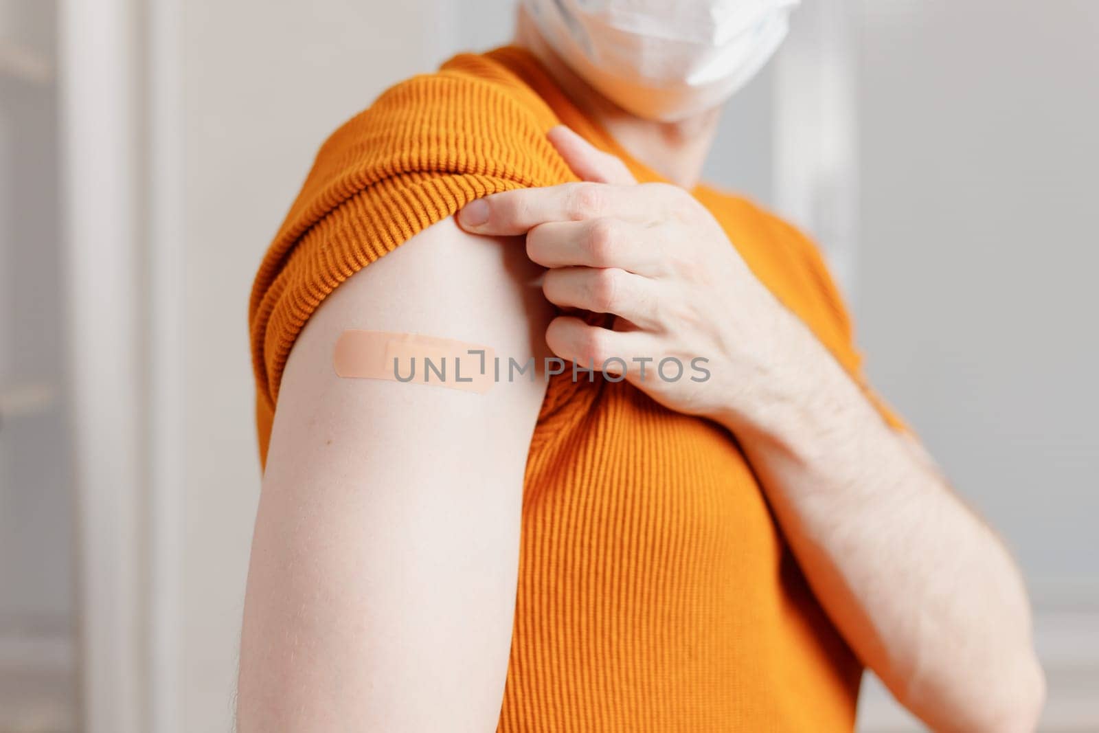 Portrait of Asian man showing his shoulder with bandage after getting a vaccination during covid-19 immunization program.