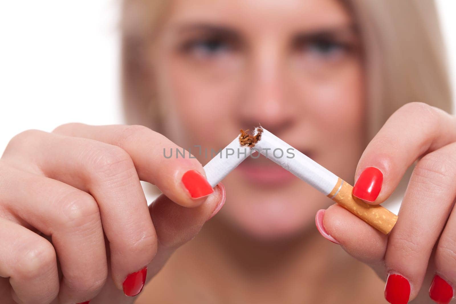 Young blonde woman breaks a cigarette stops smoking isolated against white background