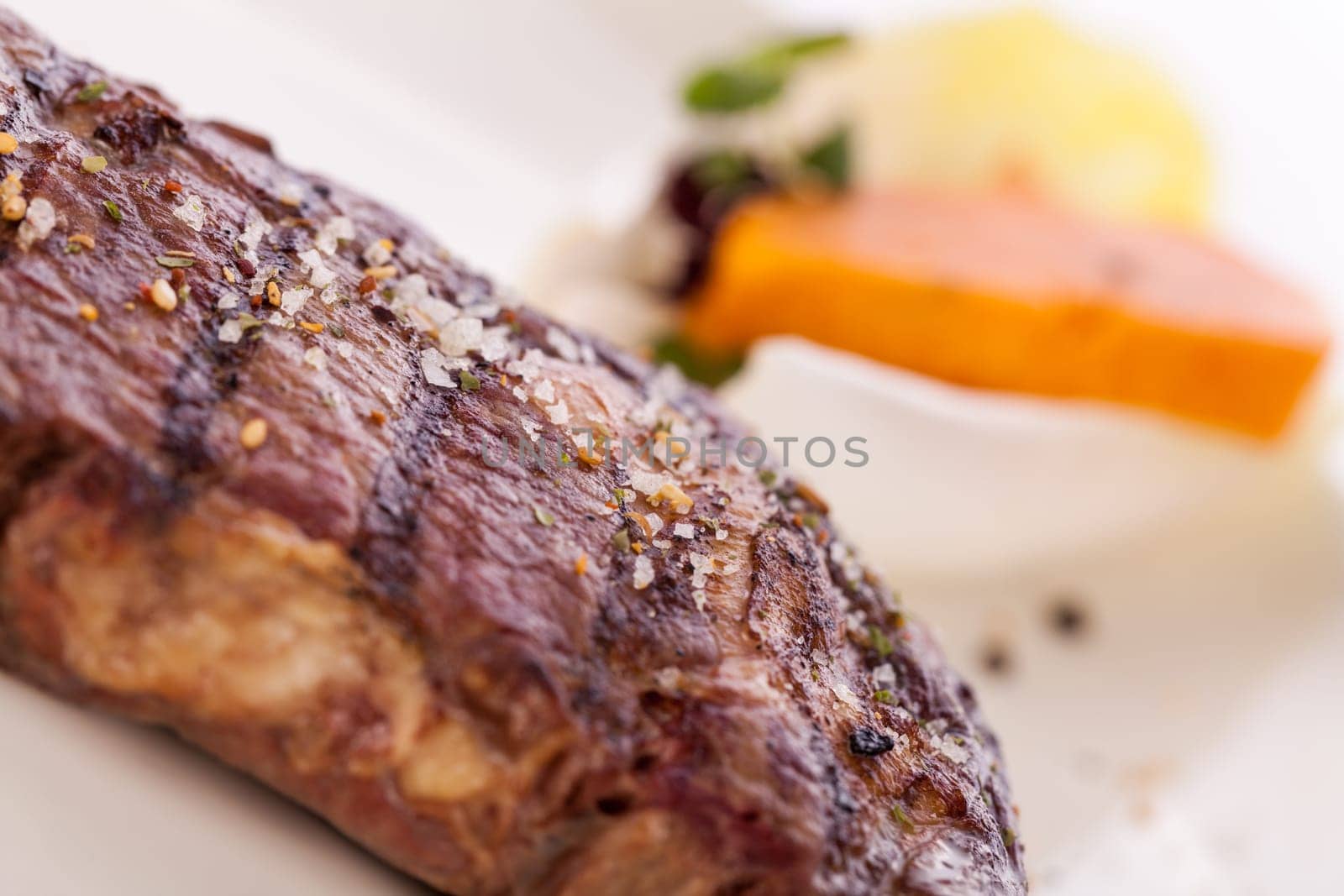 Succulent grilled beef fillet steak with homemade herb butter on a plate isolated against a white background
