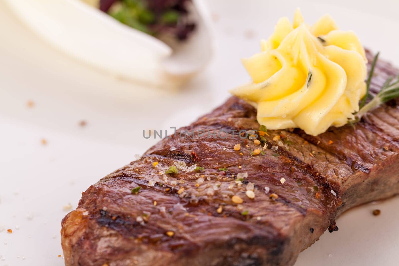Succulent grilled beef fillet steak with homemade herb butter on a plate isolated against a white background