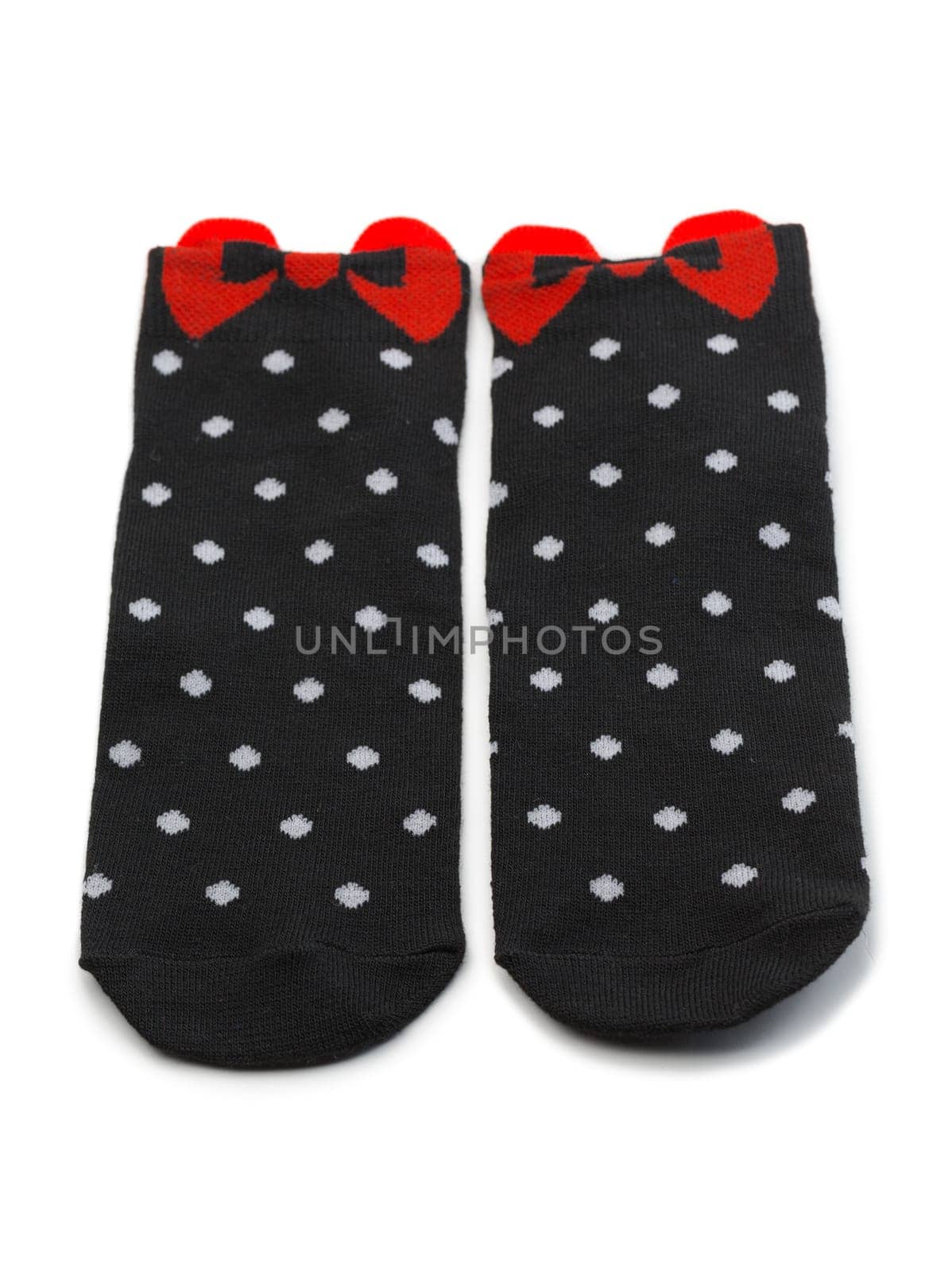 Pair of black socks with white polka dots with a red bow. Isolate.