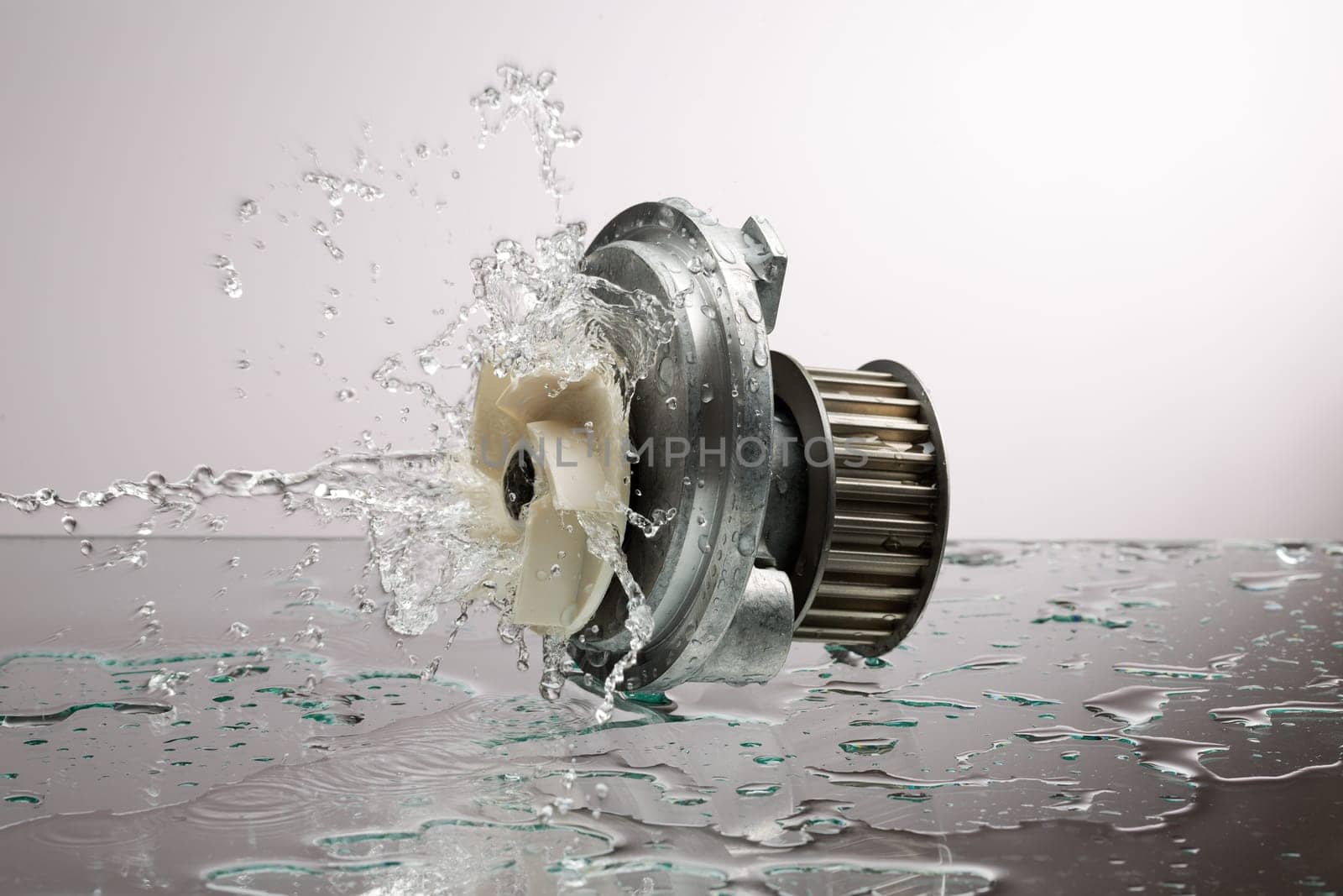Auto parts, engine cooling pump in water splash on gray gradient background