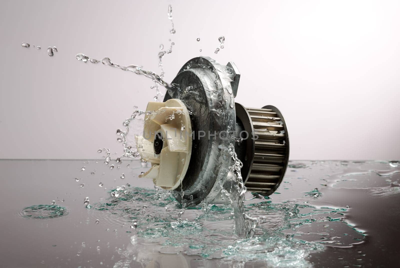 Auto parts, engine cooling pump in spurts of water on a light gradient background