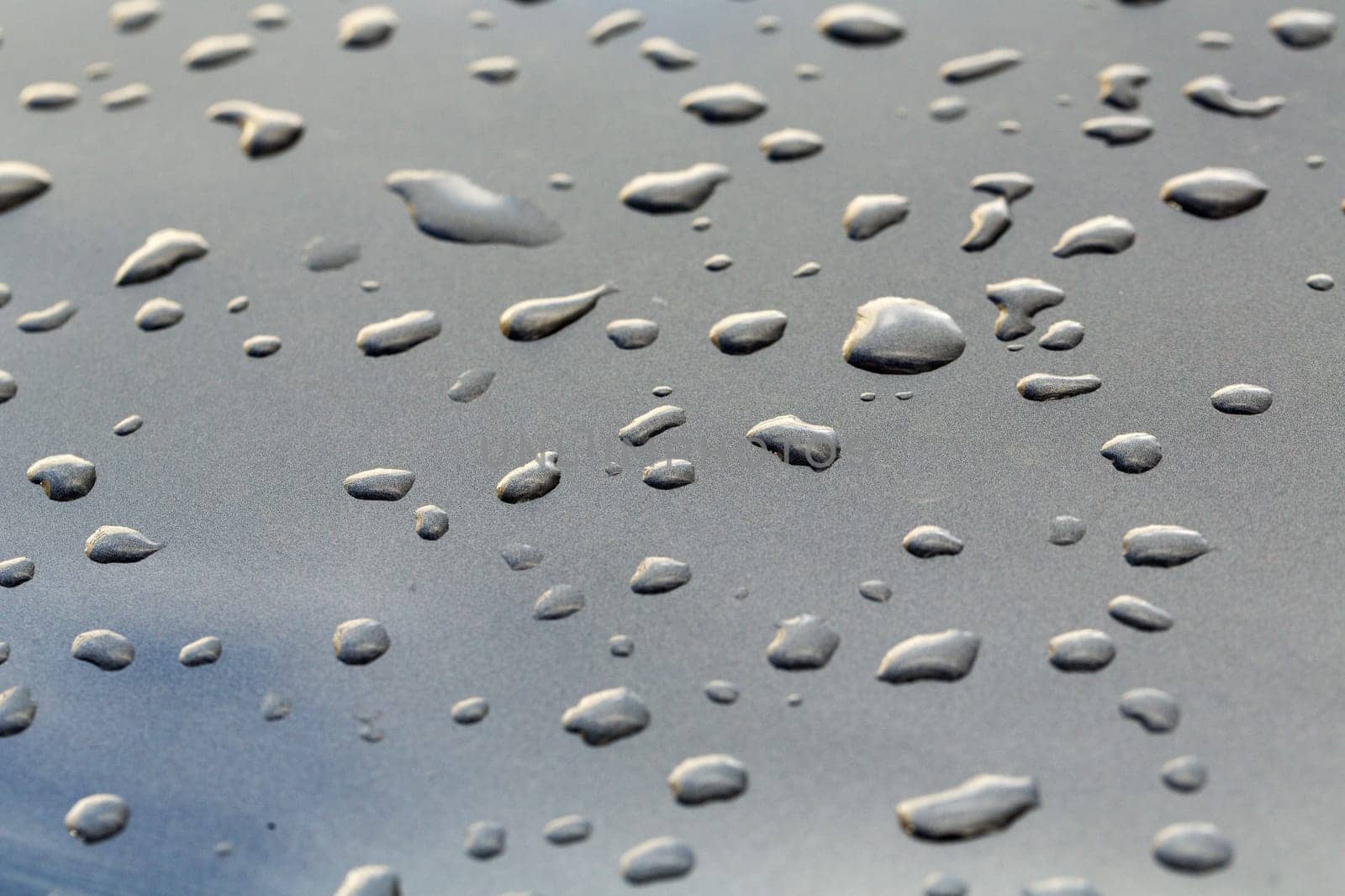 drops on a gray mirror surface which reflects the sky