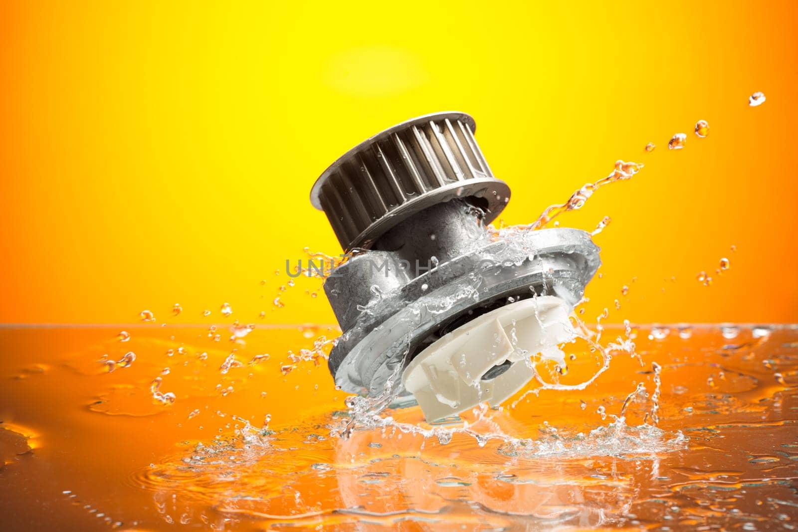 Auto parts, engine cooling pump in water splash on orange gradient background