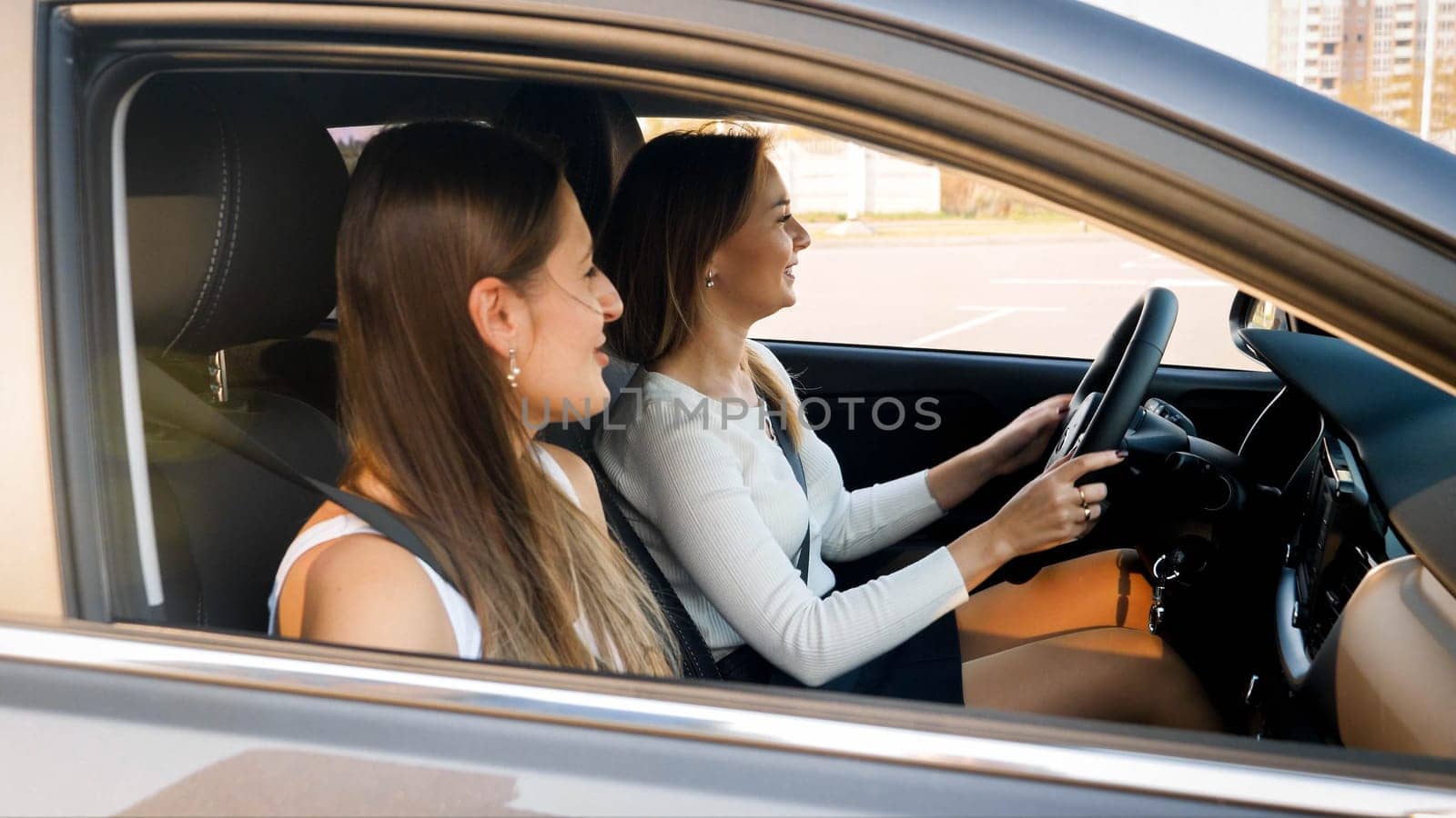 Two happy smiling girls driving a car on city street.
