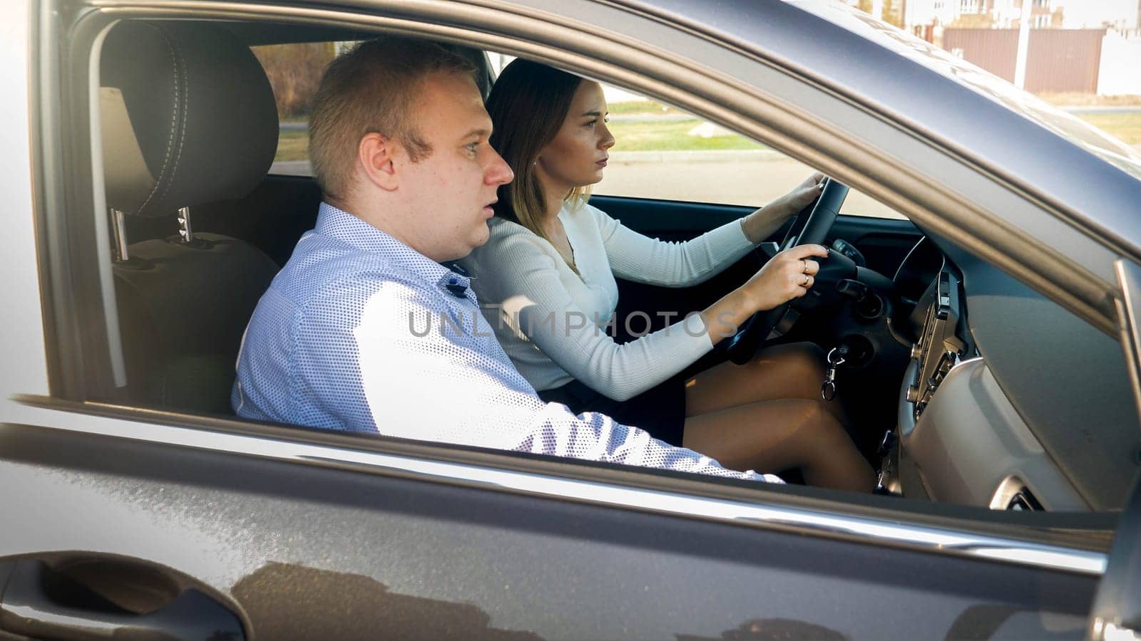 Portrait of beautiful female driver and male passenger riding in car.