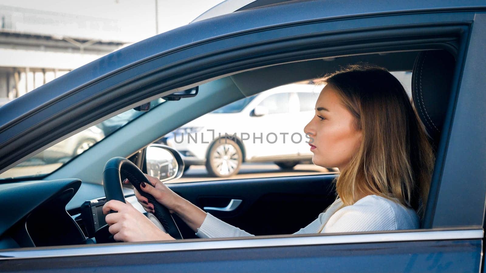 Portrait of young businesswoman driving a car on city street.