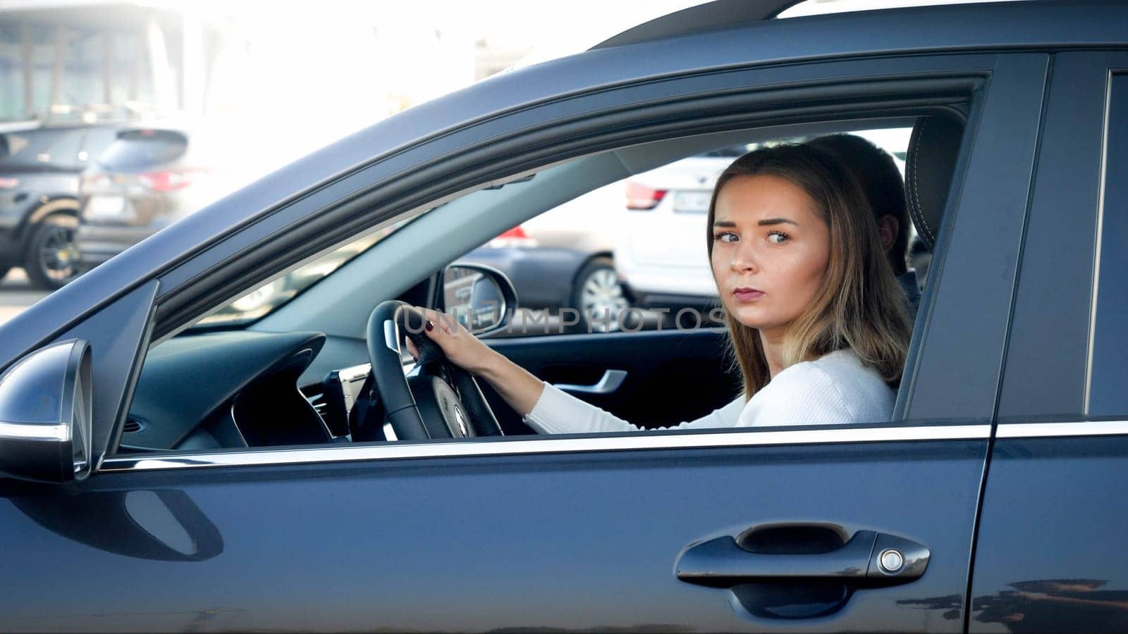 Portrait of young female driver looking out the open window while driving a car.